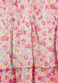 Tela floral colorida con tonos de rosa, naranja y azul. Presenta volantes fruncidos y una apariencia ligera y texturizada.