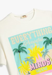 Hvid bomulds t-shirt med et farverigt grafisk print af palmer, en sol og teksten "Alt er fredeligt i vores sind Miami."