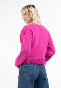 Kurzes pinkes Sweatshirt mit Fransen am Saum und an den Ärmeln. Aus weichem Material gefertigt, mit rundem Halsauschnitt und langen Ärmeln.