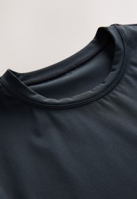 Svart atletisk tröja med en slät, elastisk textur, försedd med rundad halsringning och subtil sömnadsdetalj runt kragen.