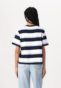 Cotton t-shirt with navy, white, and light blue horizontal stripes, short sleeves, and a crew neckline, paired with light blue jeans.