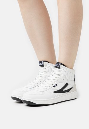 Baskets montantes avec un extérieur en cuir blanc et des accents noirs, des détails perforés, un design à lacets et une semelle en caoutchouc robuste.