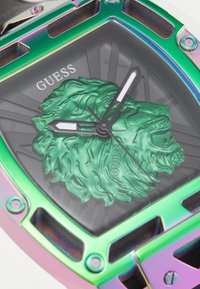 Montre carrée avec un boîtier métallique arc-en-ciel, un cadran noir et un motif de lion vert. Elle dispose d'aiguilles des heures et des minutes blanches avec des accents noirs.