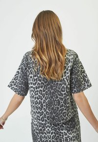 Top leopard stampato grigio e nero con vestibilità ampia, maniche corte e orlo arrotondato. Presenta un tessuto morbido e strutturato.
