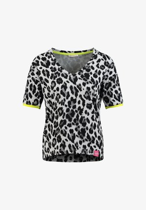 Chemise à manches courtes à imprimé léopard noir et blanc avec col en V et bordures jaune néon aux manches sur fond blanc.