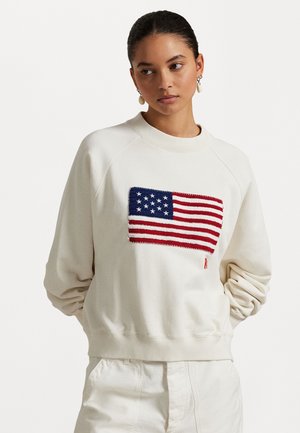 Cream sweatshirt with a knitted American flag design. Features raglan sleeves, ribbed cuffs, and a relaxed fit. Soft cotton-blend texture.