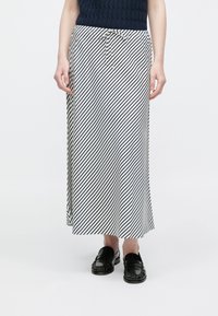 Midi-nederdel med striber i hvid og marineblå, lavet af et blødt materiale. Har snøre i taljen og en afslappet pasform. Kombinationen er med sorte loafers.