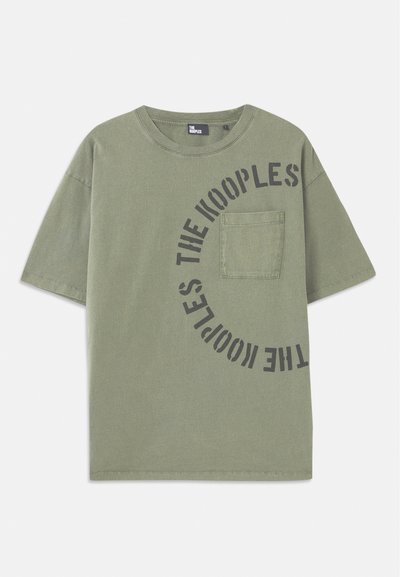 T-shirt de manga curta em verde oliva, em algodão, com uma estampa de texto preta em formato circular. Apresenta um bolso no peito e decote redondo.