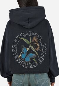 Marine blauwe hoodie met een grote afbeelding van twee vlinders en tekst. De sweatshirt heeft een ontspannen pasvorm en een capuchon met trekkoord.