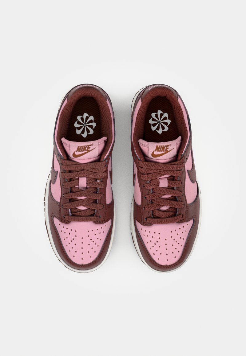 Sneaker Nike con una toma in pelle rosa e marrone, caratterizzate da una punta forata, lacci marroni e una suola in gomma bianca. Logo sulla linguetta.