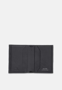 Portefeuille en cuir noir avec plusieurs emplacements pour cartes, texture lisse, accents gaufrés et un logo indiquant "GUESS GENUINE LEATHER".