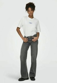 White graphic t-shirt with a blue design, paired with wide-leg gray jeans with a faded look, and black ankle boots.