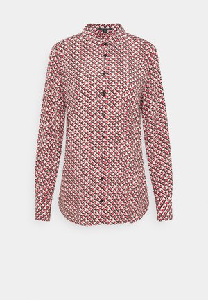 Camisa de manga larga con botones y cuello, con un patrón geométrico repetitivo en rojo, negro y blanco sobre un fondo claro.
