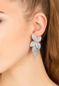 Silver floral earrings with multiple petal-like shapes, encrusted with sparkling gemstones, featuring a textured surface and elegant design.