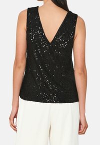 Svart ärmlös topp med V-ringning, med en textur täckt av paljetter och en figurnära silhuett.