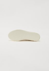 Weiße Gummisohle mit strukturiertem Oberflächenmuster in Wabenform und geprägtem Logo "TOM TAILOR." Glatte Kanten.