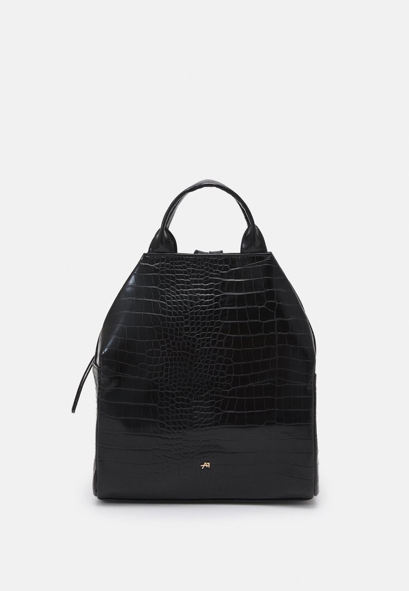 Sac à main noir à texture crocodile, forme structurée, poignées supérieures et petit logo doré sur le devant, sur un fond clair uni.