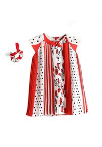 Vestido plisado rojo y blanco con lunares negros y patrones florales, combinado con una coleta de tela a juego en rojo y blanco.