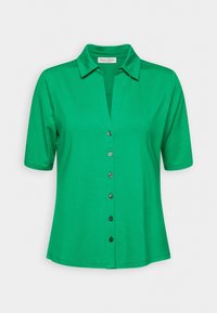 Chemisier vert à manches courtes pour femmes, avec col, présenté sur fond blanc.