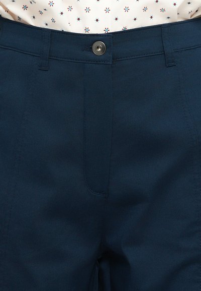 Calças azul-marinho feitas de tecido suave, com fecho de correr e botão, apresentando bolsos frontais e discretos detalhes de costura.