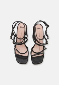 Sandalias negras de tacón con múltiples correas delgadas y punta cuadrada. Presentan una plantilla acolchada y hebillas plateadas para un ajuste ajustable.