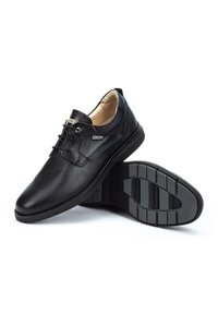 Chaussures en cuir noir avec un bout arrondi, un laçage, des détails de couture subtils et une semelle en caoutchouc texturé pour une adhérence et un soutien.