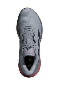 Scarpe da ginnastica grigie con tomaia in rete testurizzata, accenti neri e suola rossa. Presentano una tradizionale allacciatura e un collare imbottito.