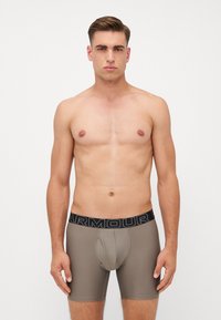 Men's brown boxer briefs with a textured fabric and a black waistband featuring the "ARMOUR" logo. Designed for comfort and support.