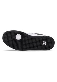 Black rubber shoe sole with a textured grip pattern, featuring a circular embossed detail and a white logo on the side.