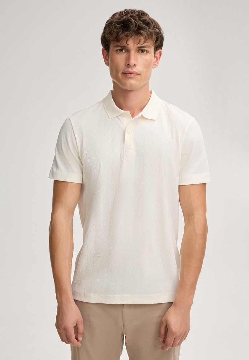 Korte mouwen polo in ivoor, met een getextureerd ruitpatroon, een zachte kraag en een knoopsluiting met drie knopen. Geaccentueerd aan de zoom.