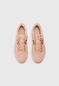 Jasnoróżowe buty sportowe z przewiewną siateczką, sznurowanym zapięciem, wyściełanym kołnierzem i białą gumową podeszwą. Subtelne logo po boku.