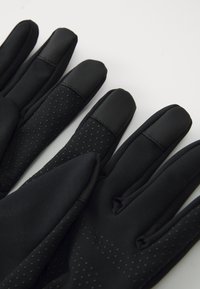 Sorte hansker med teksturerte, forsterkede fingertupper og prikkete gripe-mønstre på fingrene og håndflatene, vist på en hvit bakgrunn.