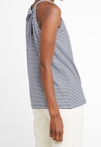 Top senza maniche a righe nei colori navy e bianco, con dettaglio a nodo sul retro e vestibilità comoda, realizzato in tessuto morbido.