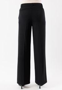 Pantaloni neri a gamba larga in tessuto liscio, con vita piatta, passanti per la cintura, due tasche posteriori e pieghe sottili davanti.