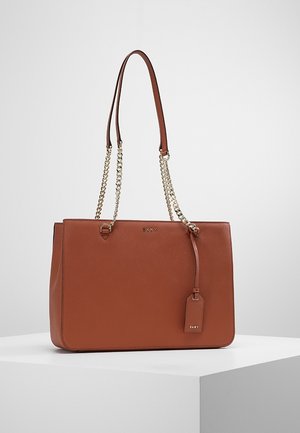 Sac fourre-tout en cuir marron avec des poignées plates doubles et des accents en chaîne. Il dispose d'une plaque logo et d'une étiquette amovible pour plus de détails.