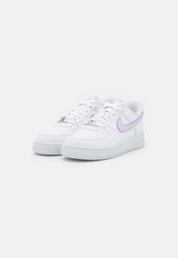 Bílé kožené tenisky s hladkým povrchem, kulatou špičkou, předním šněrováním a světle fialovým akcentem značky Nike na boční straně.