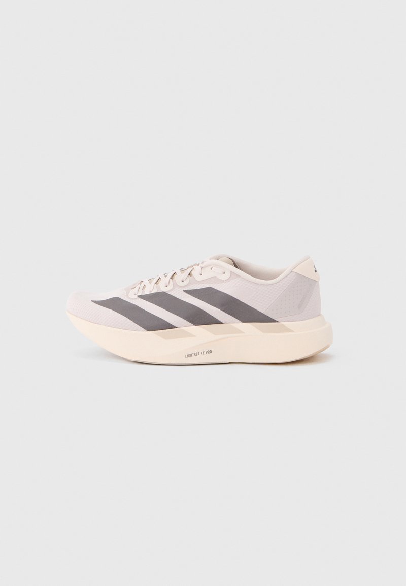 Lekkie sportowe buty w jasnoróżowym i szarym kolorze, z siateczkową cholewką, trzema ciemnymi paskami oraz grubą kremową podeszwą oznaczoną napisem "LIGHTSTRIKE PRO".