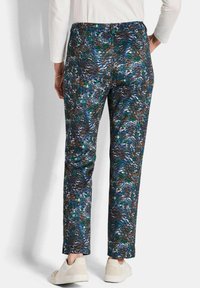 Pantaloni a righe floreali con texture in tonalità di blu, verde e marrone, con design a gamba dritta e vita elastica, indossati con scarpe leggere.