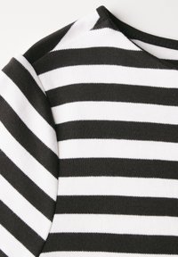 Textil a rayas en blanco y negro con una textura suave. Presenta un escote redondo y costuras de hombro ligeramente caídas.