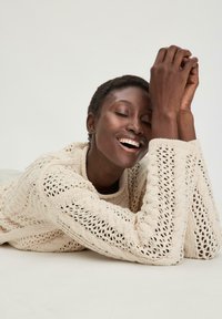 Strickpullover in sanftem Creme mit einem strukturierten, offenen Muster. Runder Ausschnitt und lange Ärmel, mit rippenförmigen Bündchen und Säumen.