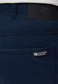 Pantalons bleu marine en mélange de coton ; dotés d'une étiquette de ceinture en faux cuir avec le logo "s.Oliver" et une étiquette indiquant "ELEVATED CASUAL".