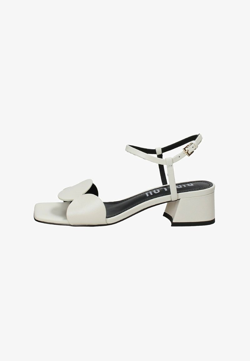 Sandal in pelle bianca con punta quadrata, ampia fascia frontale con design floreale, cinturino alla caviglia regolabile e tacco basso a blocco.