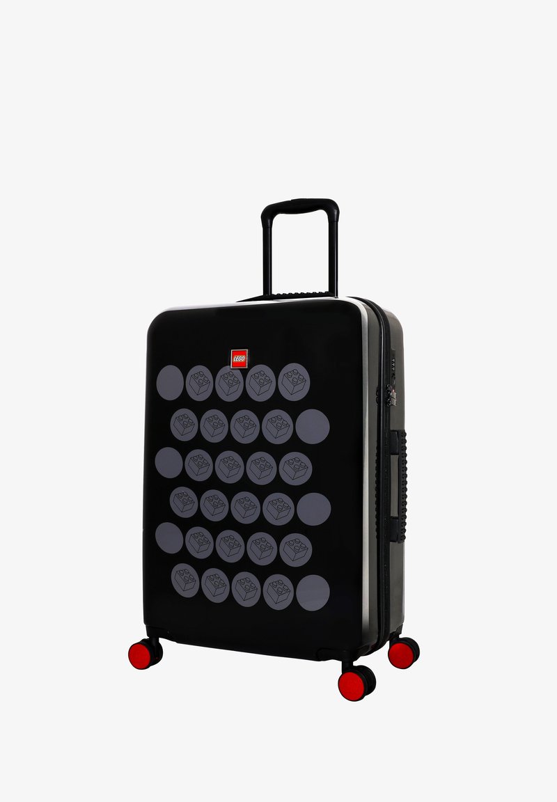 Černý tvrdý kufr s designem LEGO kostek, obsahující 20 šedých kruhových vzorů. Má teleskopickou rukojeť a červená kola.