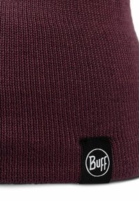 Maroon knit beanie with ribbed texture and a sewn-in black fabric label featuring the white "Buff" logo.