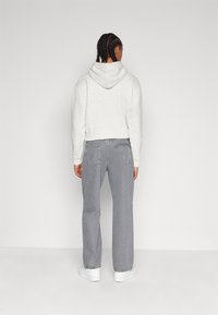 Cropped gray hoodie with a hood, paired with gray wide-leg jeans. White sneakers complete the outfit. Back view with no patterns or accents.