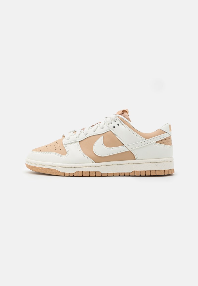 Sneaker in pelle bianca e marrone chiaro con punta perforata, colletto imbottito e suola in gomma, caratterizzate da un discreto logo Nike.