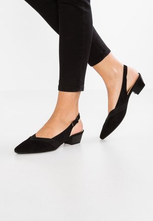 Zwarte suède slingback schoenen hebben een spitse neus, een kleine blokhak en een contrasterende hoekige band aan de voorkant.