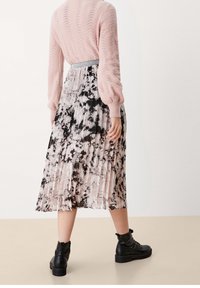 Gonna plissettata floreale con motivi neri e rosa, abbinata a un maglione lavorato a maglia rosa chiaro e stivali neri alla caviglia. Inclusa una cintura con dettagli in argento.