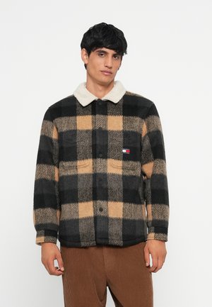 Giacca in pile a quadri con una combinazione di colori beige, nero e marrone, caratterizzata da un colletto in sherpa bianco e chiusura con bottoni frontale.