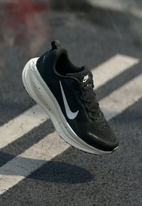 Schwarzer Laufschuh mit strukturiertem Obermaterial, weißem Swoosh-Logo und leichtem Sohlenbereich. Verfügt über Schnürsenkel und eine gepolsterte Ferse für mehr Komfort.